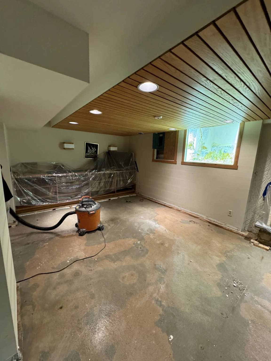 Basement floor exposed during preparation with furniture protected nearby