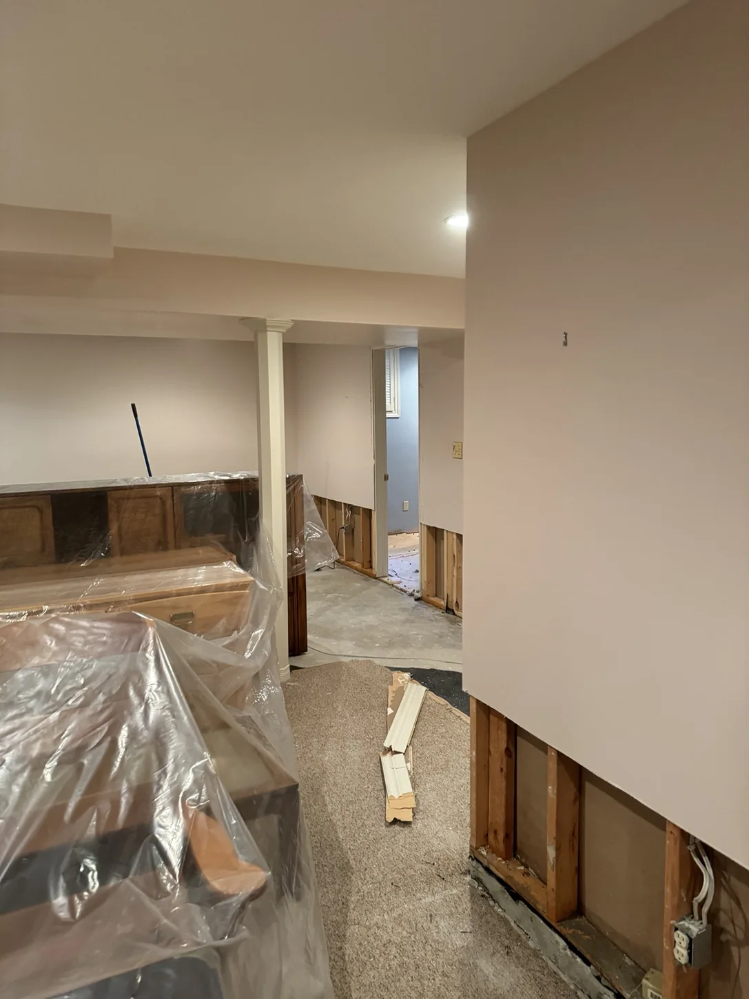 Basement furniture protected by plastic sheeting during renovation