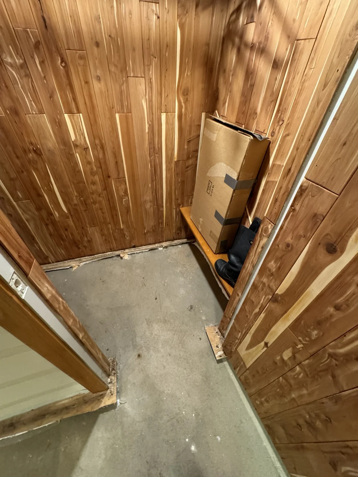Wood-panelled basement room with the existing floor covering removed