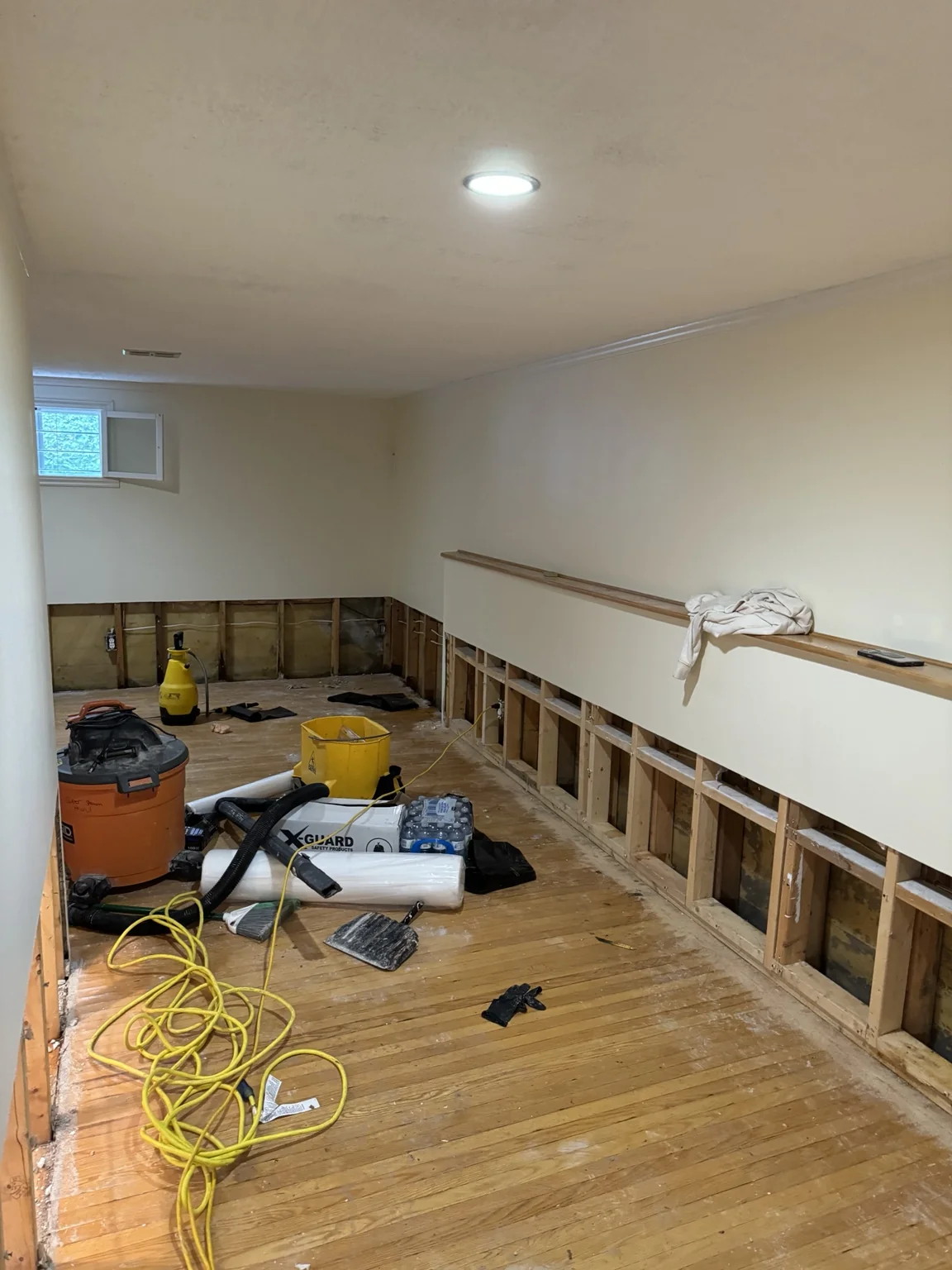 Lower basement wall opened with tools and materials on the floor