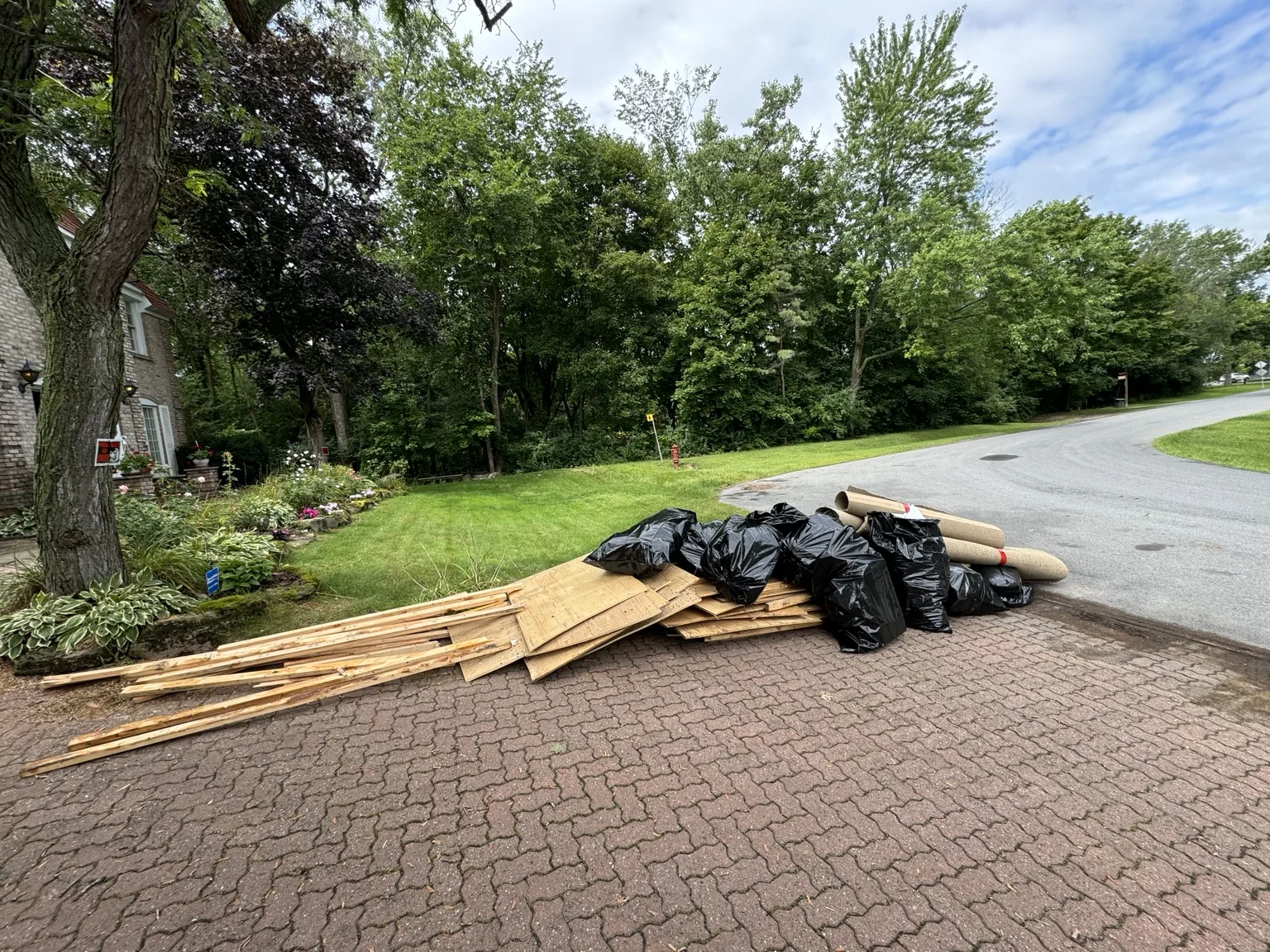 Removed boards and bagged renovation debris staged on a driveway