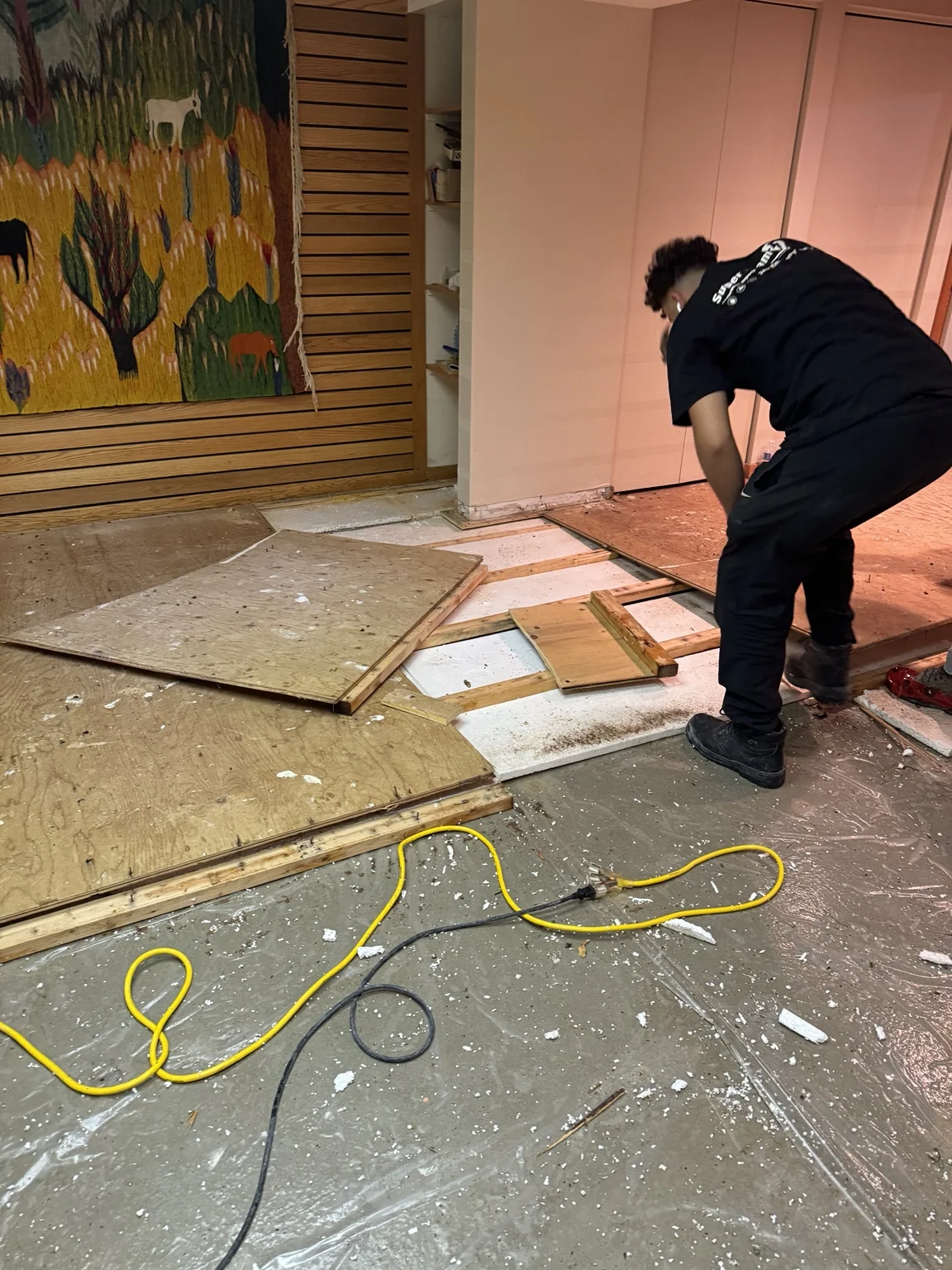 Worker lifting existing flooring during interior demolition